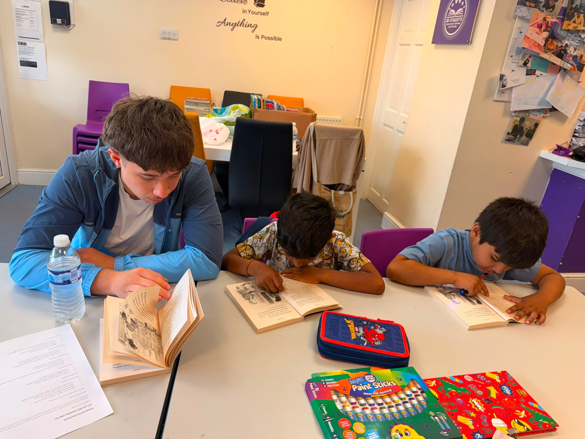 Children and a youth mentor reading together at a Be-Etiquette community session