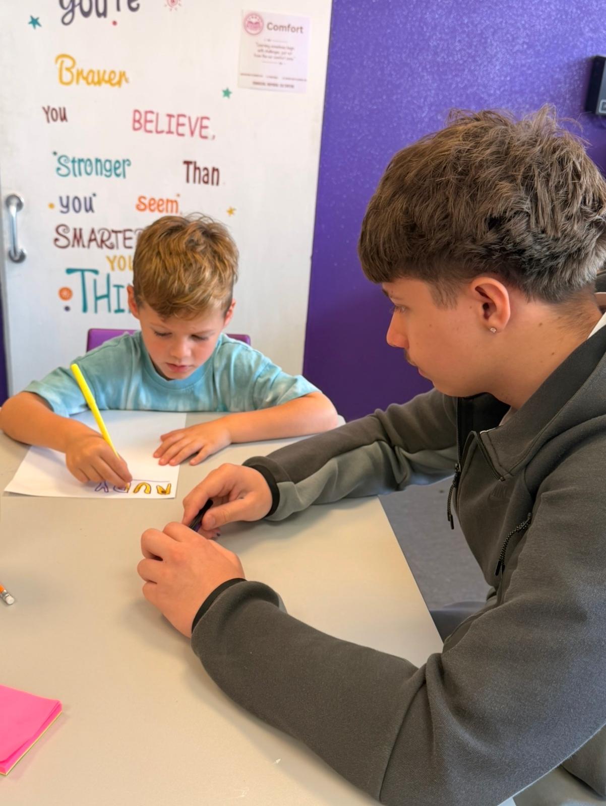 A mentor supporting a child with a writing activity
