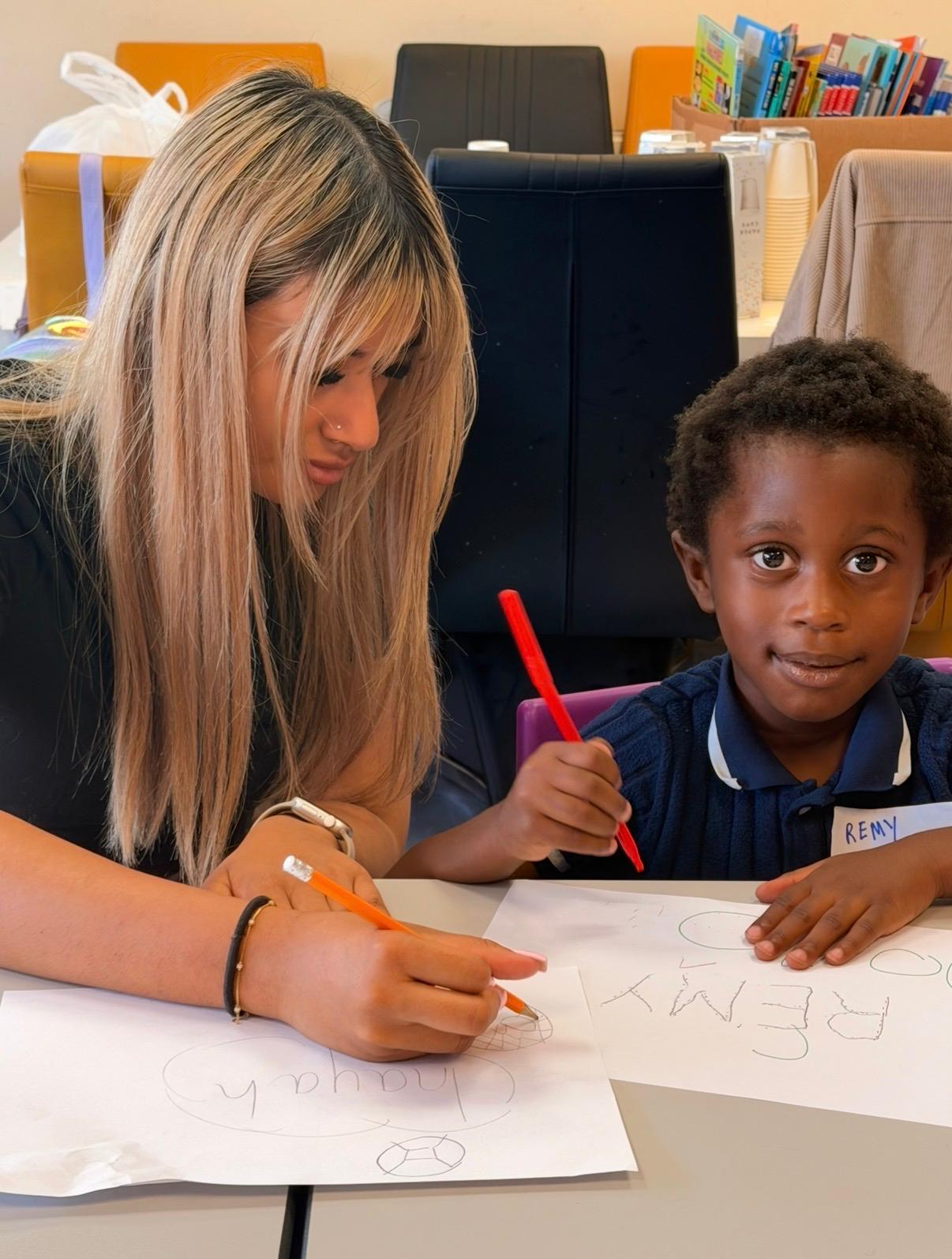 An adult drawing alongside a child during a learning activity